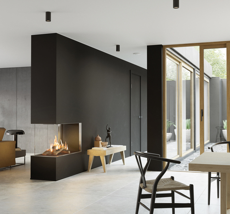 VISIO 90 RD gas fireplace fits perfectly as a room divider in a black wall between the living room and dining room and gives structure to the simply decorated living space