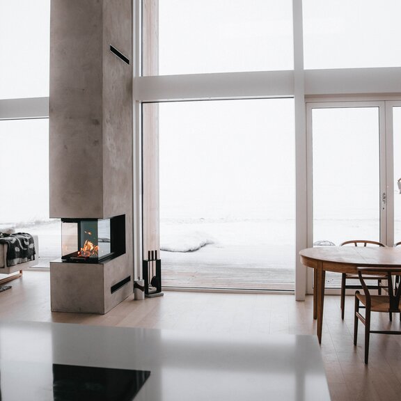 Wood fireplace VISIO 3:1 act as a room divider between the dining room and living room in a modern house somewhere in the north