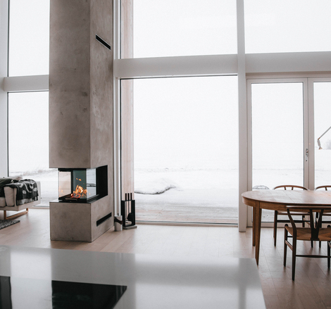 Wood fireplace VISIO 3:1 act as a room divider between the dining room and living room in a modern house somewhere in the north