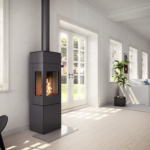 Wood stove NEXO 140 in black with steel door and two side windows in a bright living room area