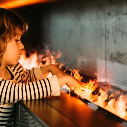 A child holds his hands in the cold water vapour flames of the Cassette 1000 electric fire from Dimplex